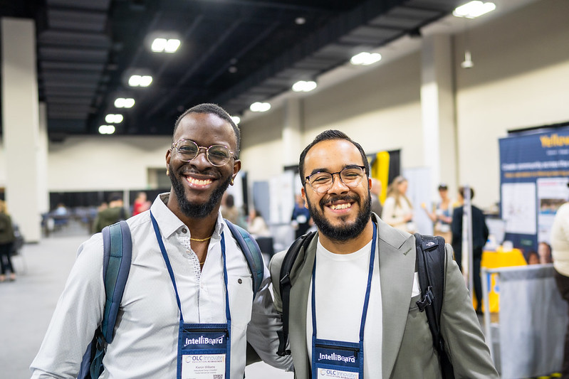 Two men at OLC Innovate 2024 stand together and smile for a photo