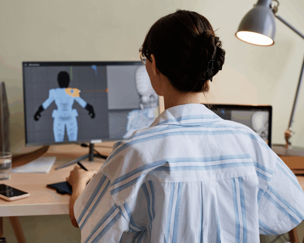 An over-the-shoulder photo of a female student using a 3D modeling program on a desktop computer.