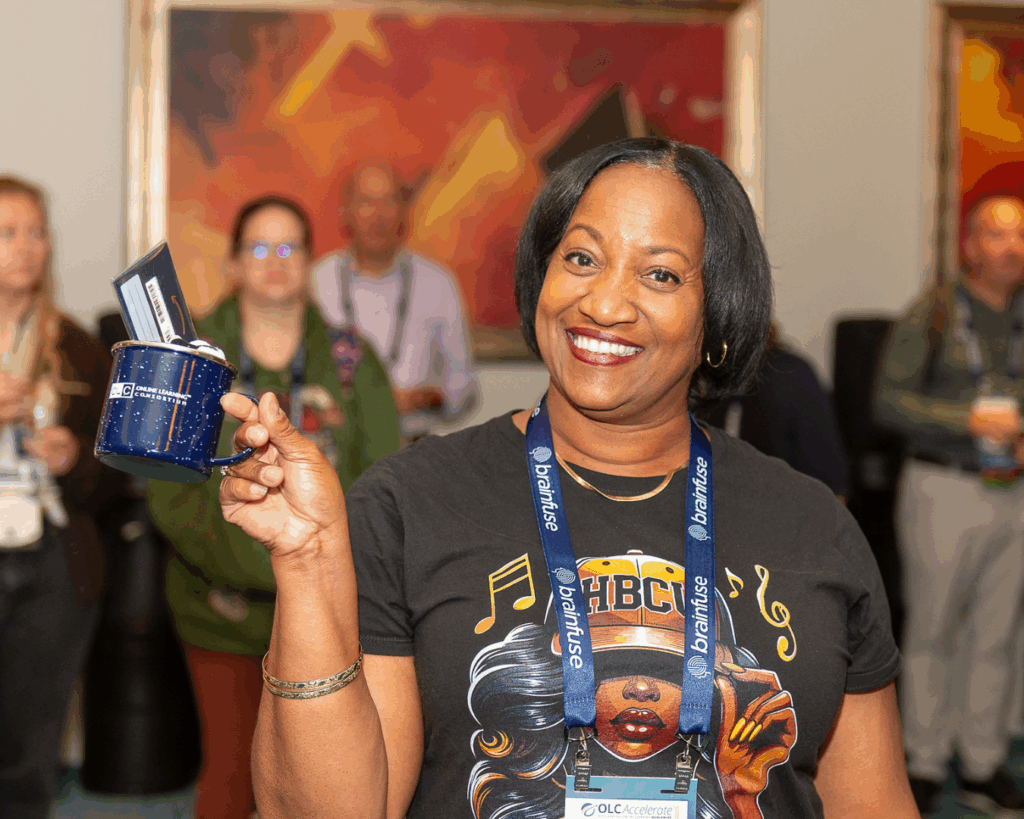 A photo of a woman at OLC Accelerate 2025 holding up an OLC-branded mug with a gift card inside.