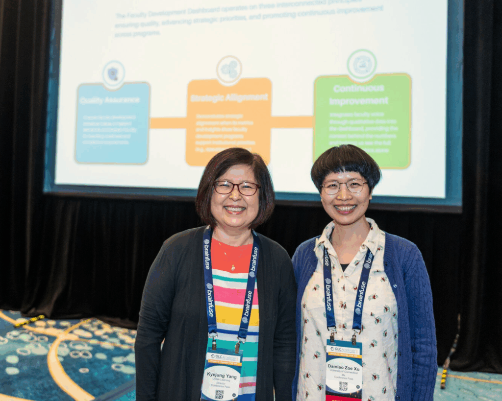 Two presenters at OLC Accelerate 2025 stand and pose for a photo together in front of their slideshow presentation.