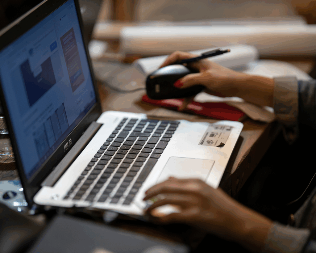 Dark photo of a person's hands on their laptop, browsing a webpage.
