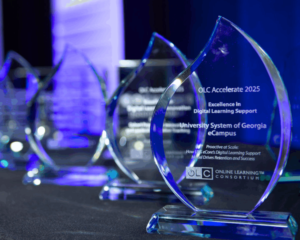 A close up photo of a row of glass award statuettes engraved with the OLC Accelerate 2025 recipients.