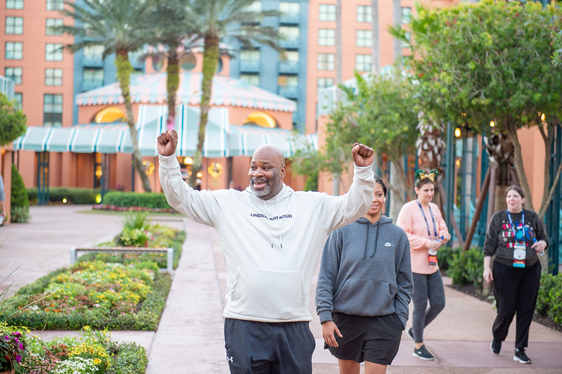 An OLC Accelerate 5K runner holding his hands up in celebration as he finishes the race.