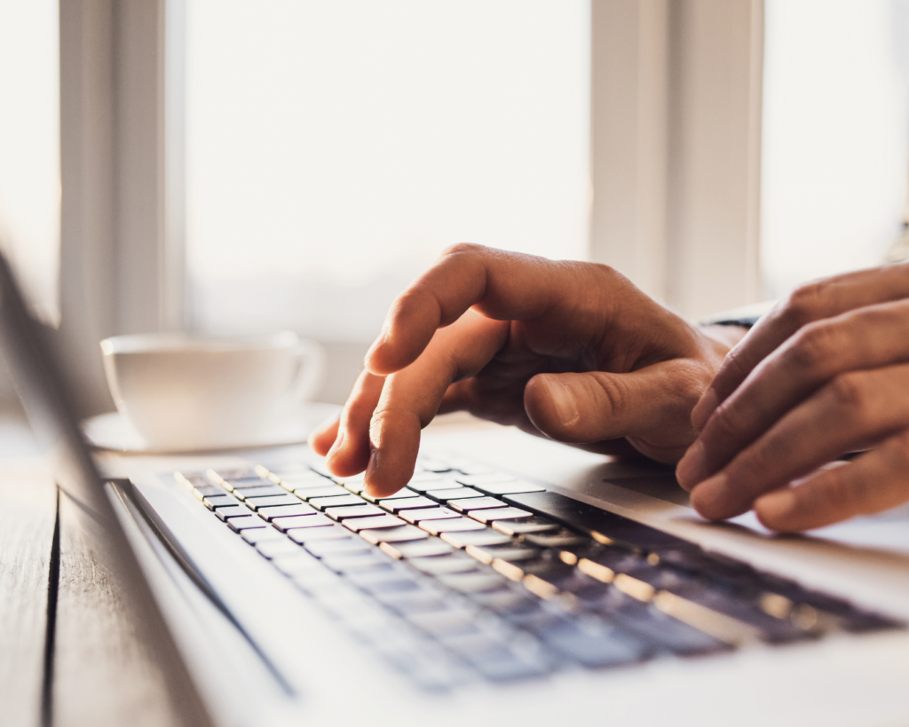 Close up, saturated photo of a person's hands typing on a laptop keyboard.
