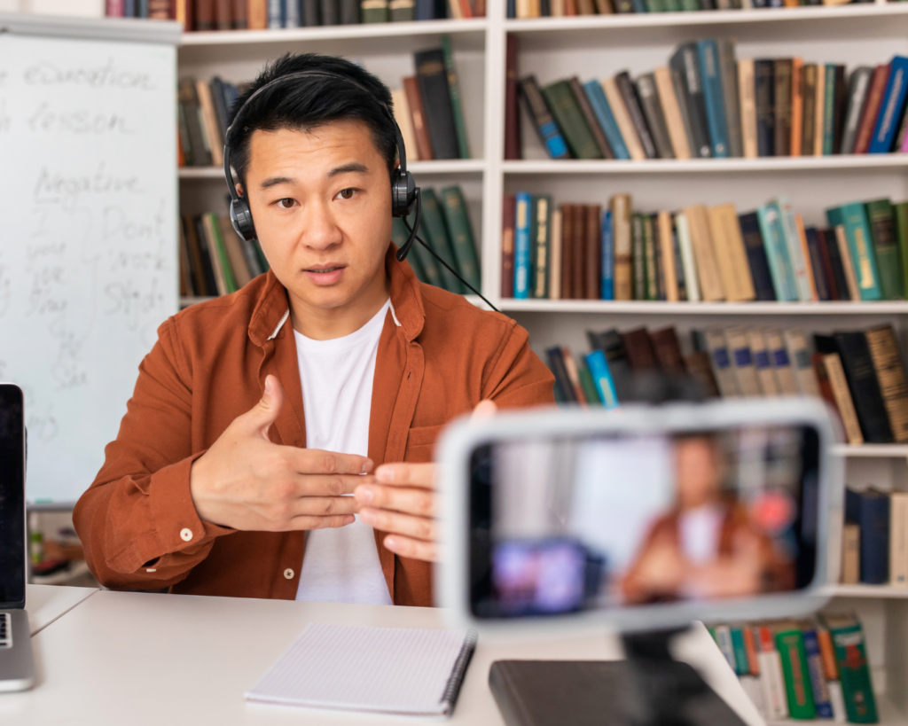 Photo of a male teacher recording a lecture with a smartphone.