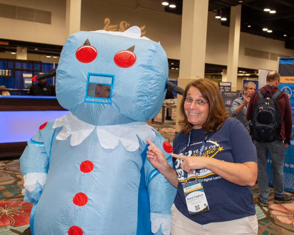 Photo of Cheryl Fulghum posing for a photo with someone in an inflatable Jetsons cartoon character costume at OLC Accelerate 2025