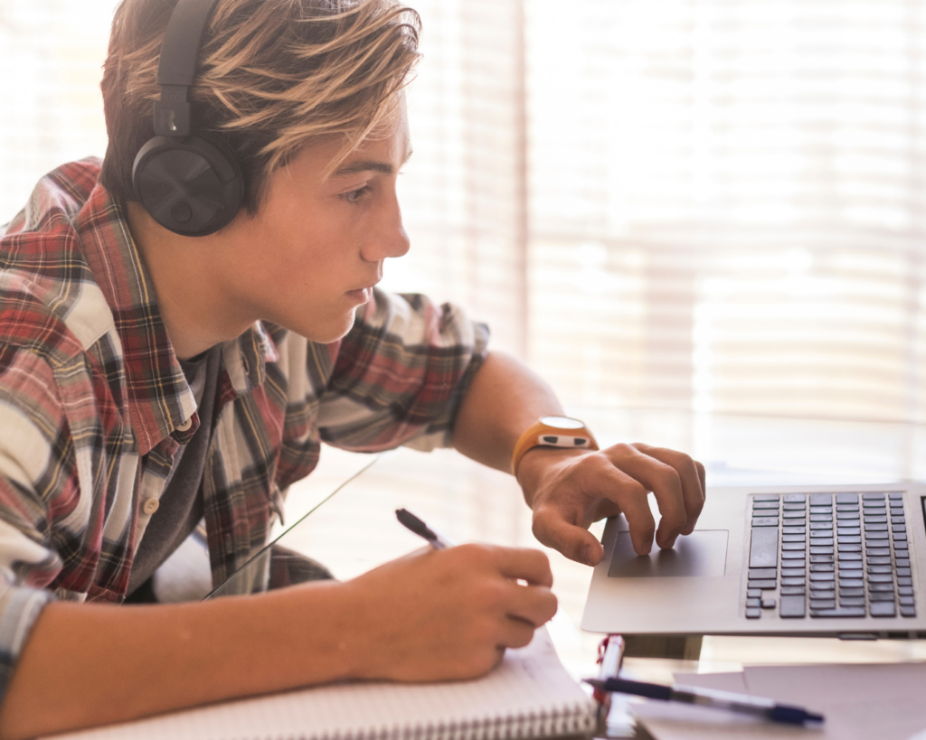 Close up photo of a young man studying on a laptop