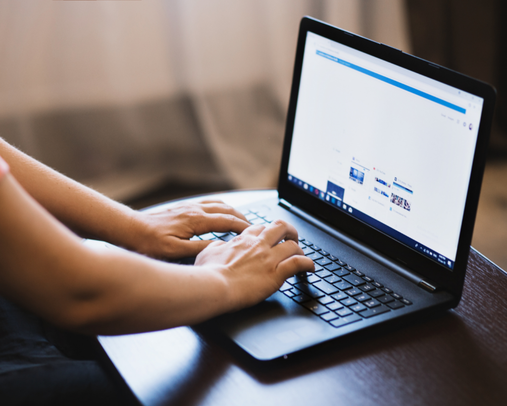 Photo of a person's hands using a laptop, navigating a website