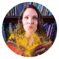 Headshot of Dr. Lisa Hassler. She holds an open book and blows gold glitter out of it towards the camera.